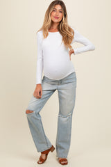 woman wearing a white long sleeve maternity top and distressed light blue maternity jeans with a visible baby bump