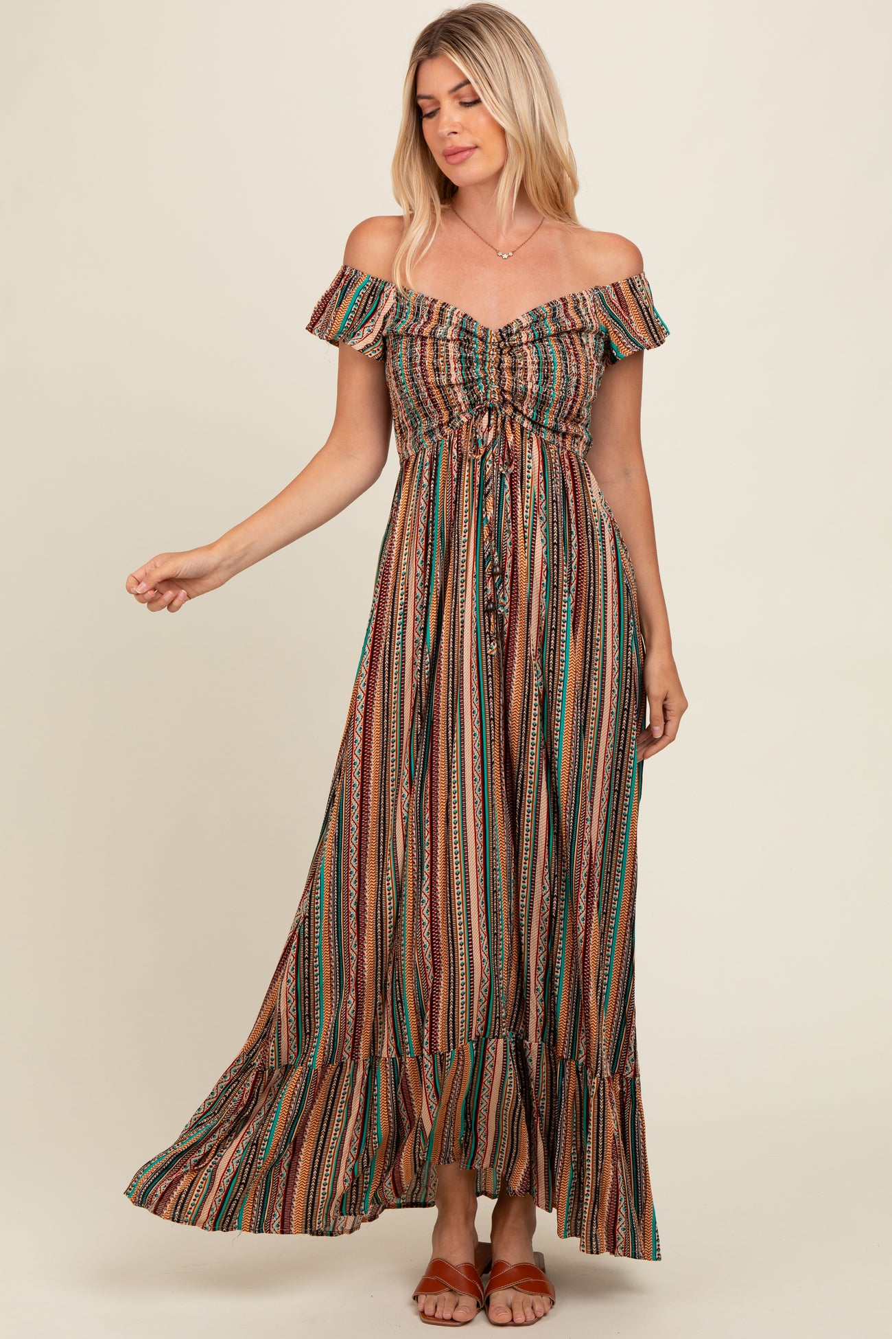 woman wearing a brown striped off-shoulder maxi dress with a cinched waist and ruffle hemline