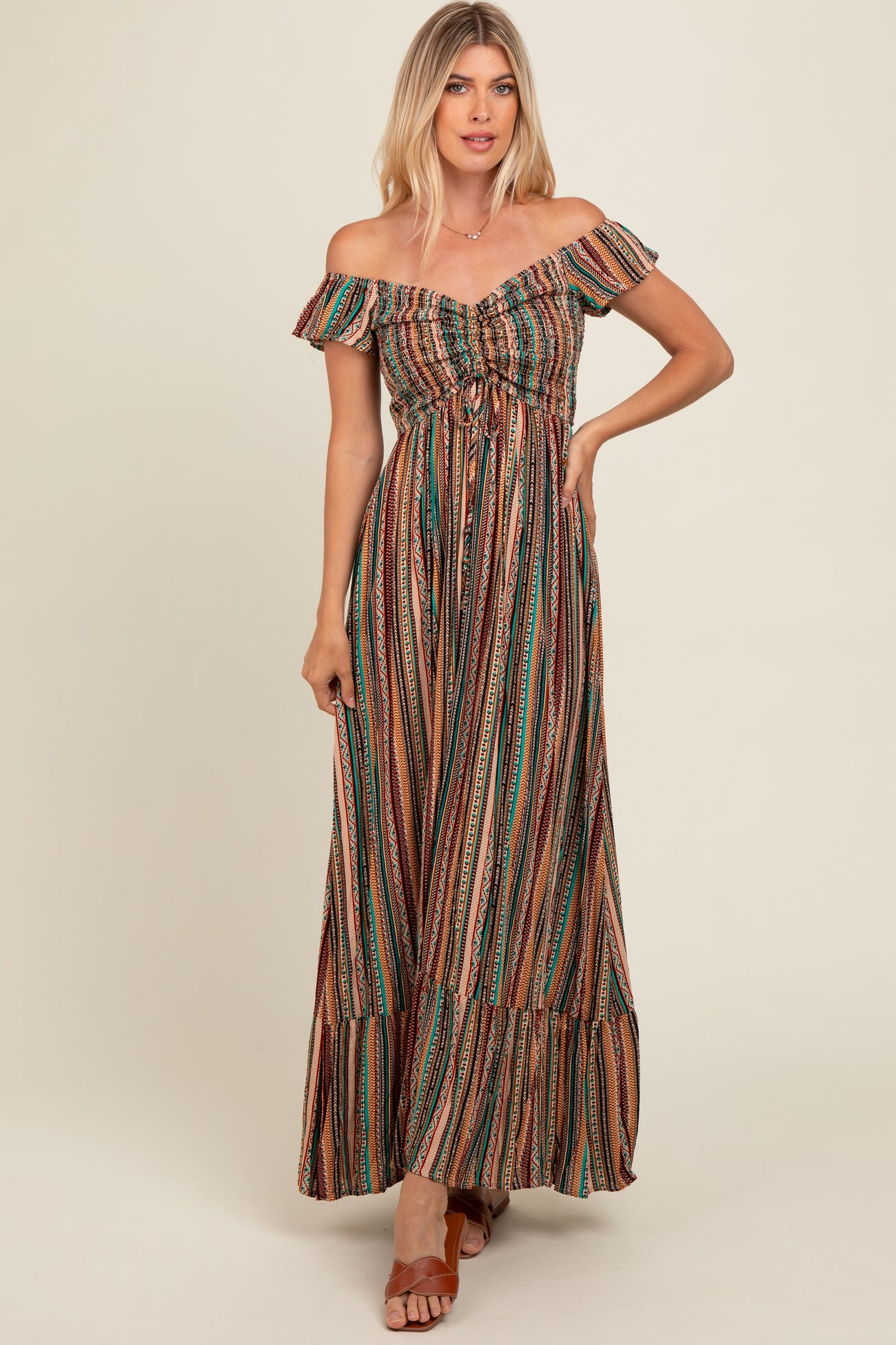 woman wearing a colorful striped off-the-shoulder maxi dress with a tie detail at the waist