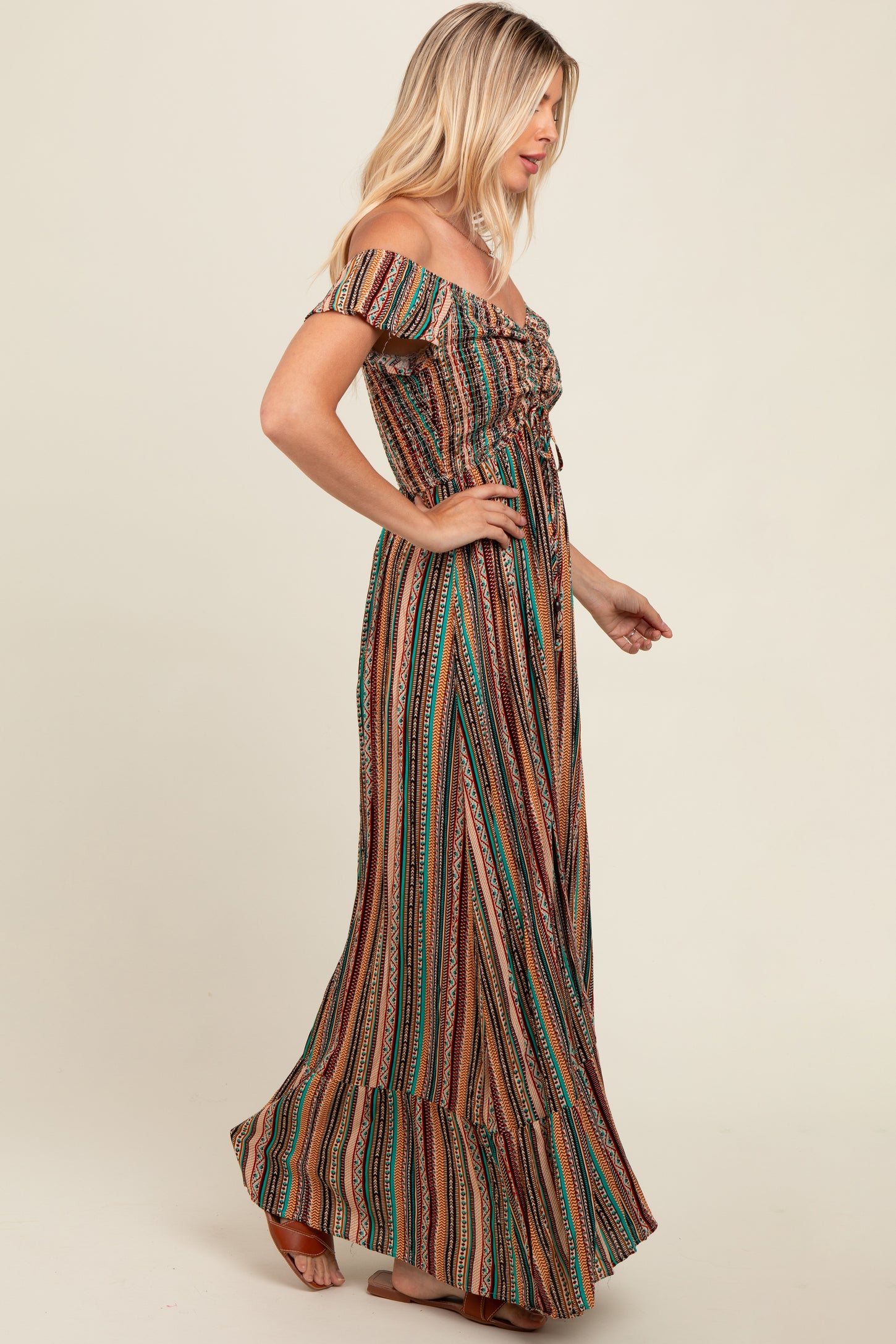 woman wearing a colorful off-the-shoulder maxi dress with vertical stripes and a ruffled hem