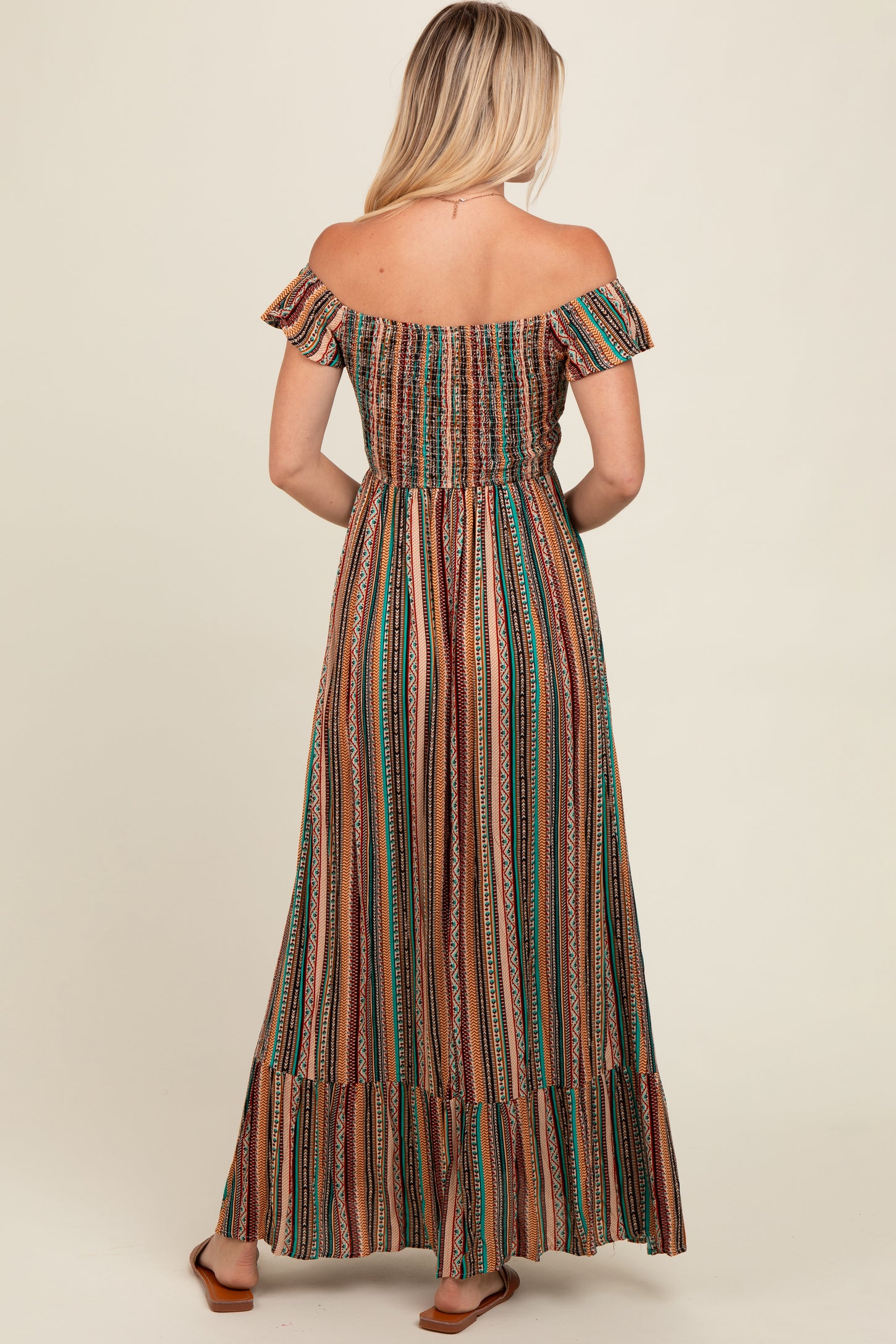 woman wearing a brown and green striped off-shoulder maxi dress with a smocked bodice and ruffled hemline, shown from the back