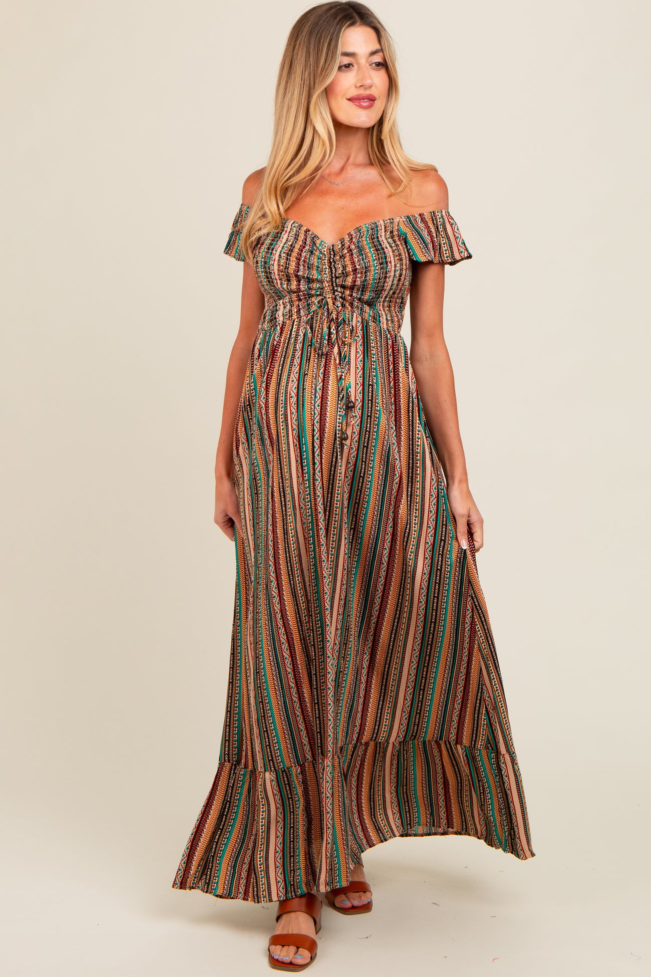 woman wearing a striped off-the-shoulder maternity maxi dress with a drawstring detail and flowing skirt, showing baby bump