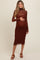 woman wearing a brown long sleeve maternity dress with a sheer top layer and baby bump visible
