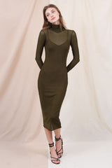 woman wearing an olive green long sleeve fitted dress with a sheer neckline and strappy heels