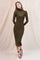 woman wearing an olive green long sleeve fitted dress with a sheer neckline and strappy heels