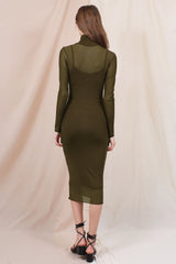 woman wearing a fitted olive green long sleeve midi dress with a sheer overlay and a mock neck