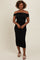 woman wearing a black off-shoulder bodycon midi dress with ruching details and slip-on beige sandals