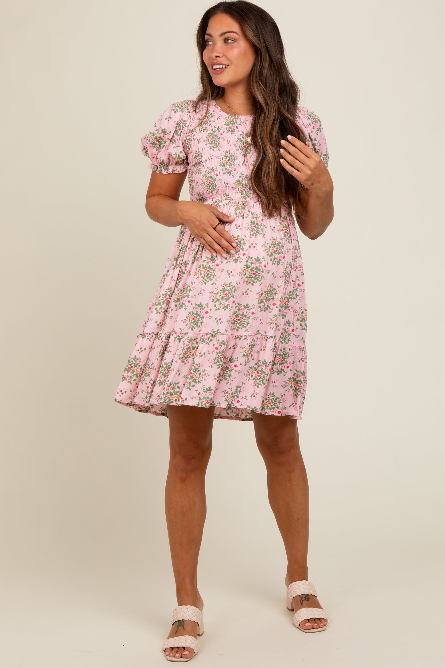 woman wearing a pink floral maternity dress with puff sleeves and a baby bump visible