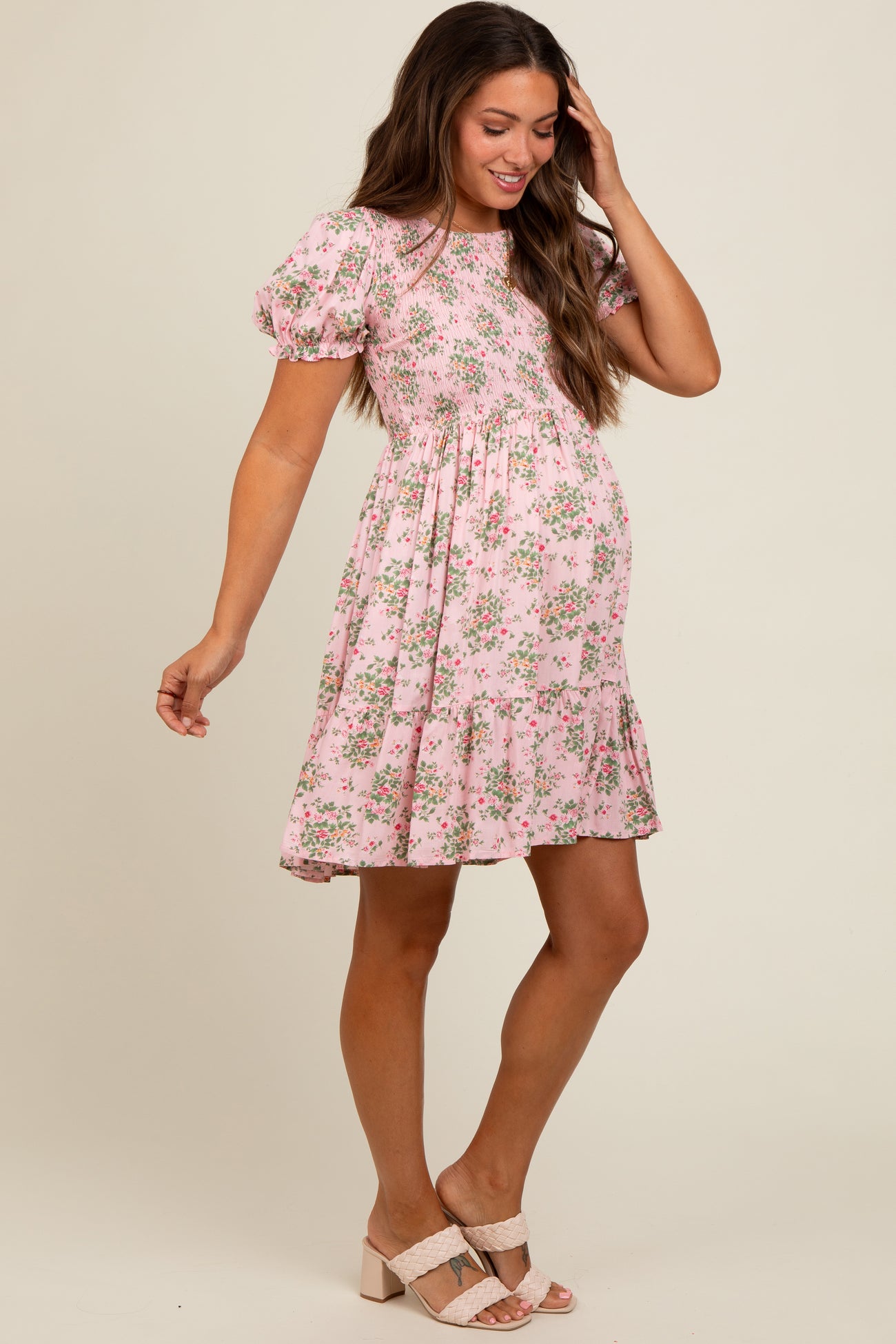 woman wearing a pink floral short sleeve maternity dress with a tiered skirt and a visible baby bump