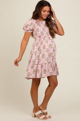woman wearing a pink floral short sleeve maternity dress with a tiered skirt and a visible baby bump