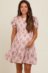 woman wearing a short puff sleeve pink floral maternity dress with a tiered skirt and smiling at the camera