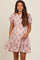 woman wearing a short puff sleeve pink floral maternity dress with a tiered skirt and smiling at the camera