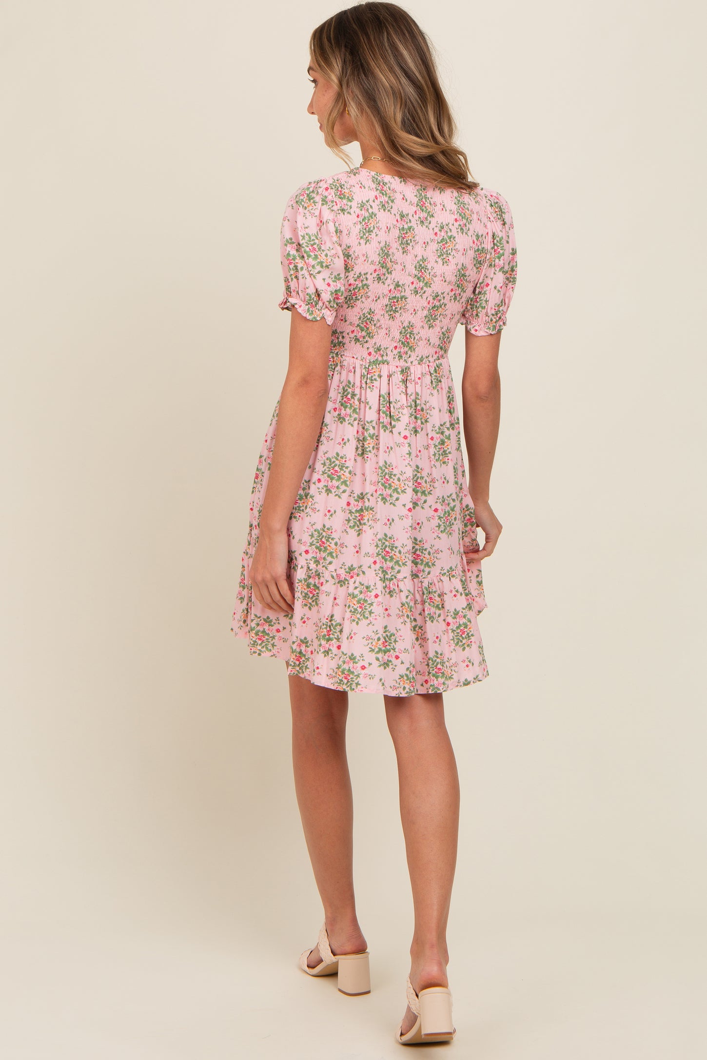 woman wearing a pink floral short sleeve dress with a tiered skirt and puff sleeves, shown from the back