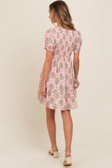 woman wearing a pink floral short sleeve dress with a tiered skirt and puff sleeves, shown from the back