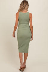 woman wearing a sage green ribbed midi maternity dress, showing a form-fitting silhouette from the back