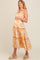 woman wearing a flowy orange floral maternity dress with ruffle straps and a visible baby bump