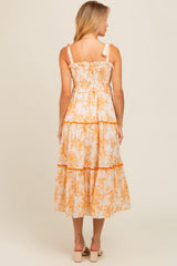 woman wearing a back view of a white midi dress with orange floral print and ruffled straps