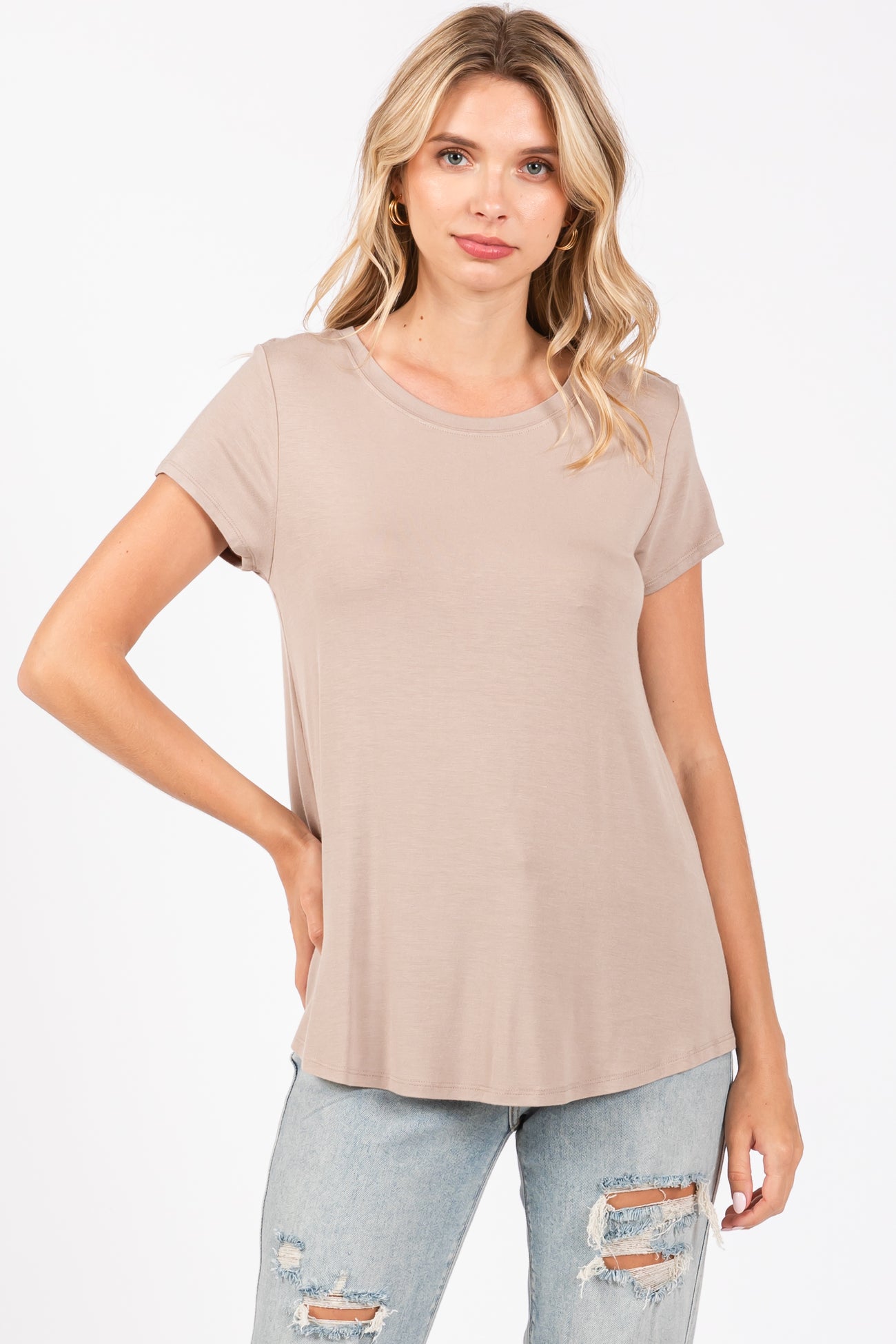 woman wearing a light taupe short sleeve top paired with distressed light blue jeans