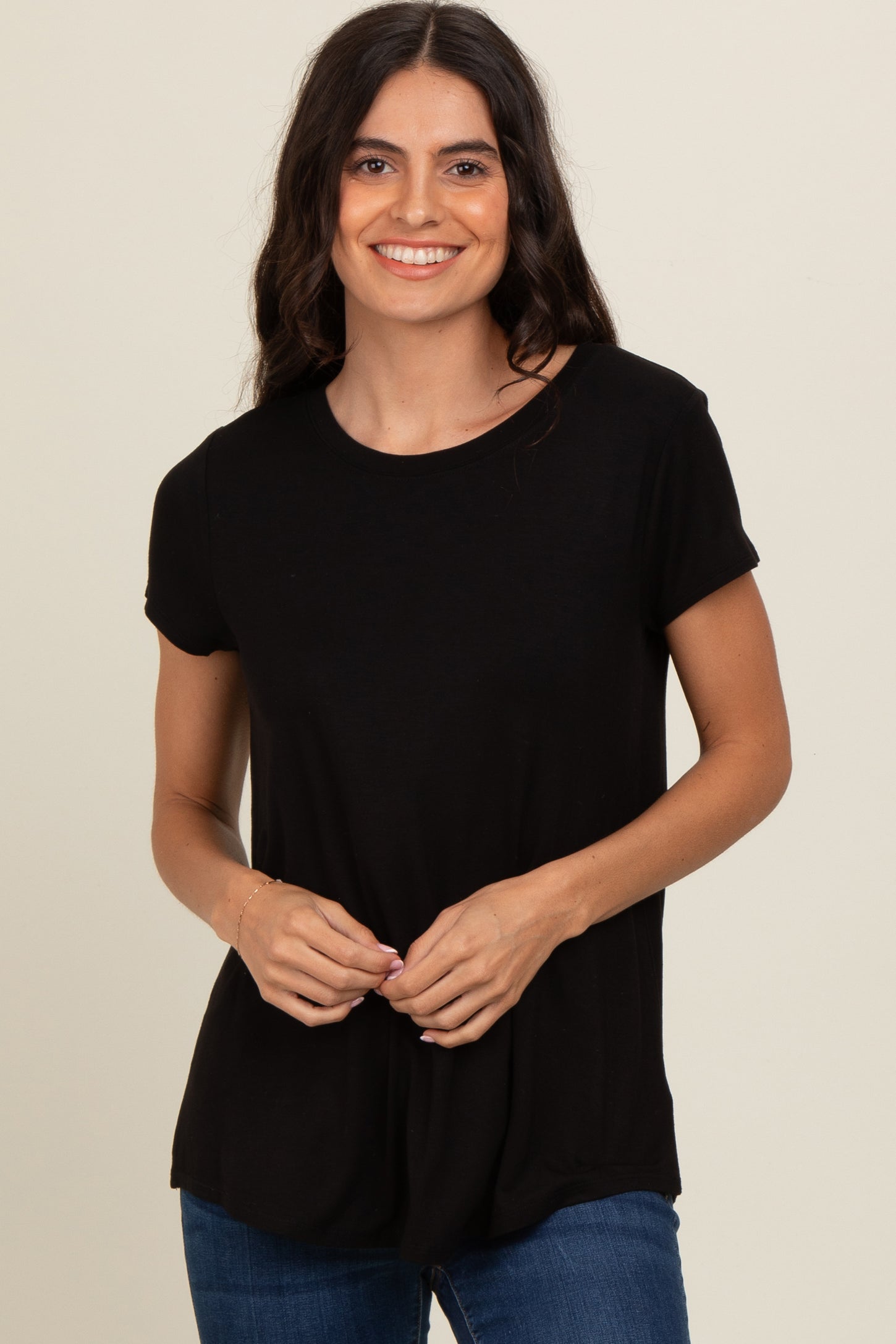 woman wearing a black short sleeve t-shirt and blue jeans, smiling at the camera