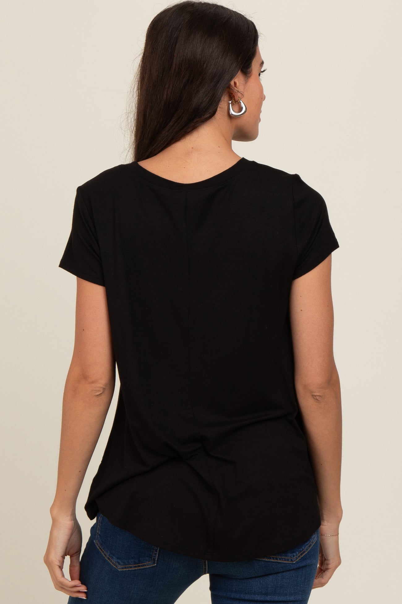 woman wearing a black short sleeve top, showing the back view with a curved hem and a relaxed fit