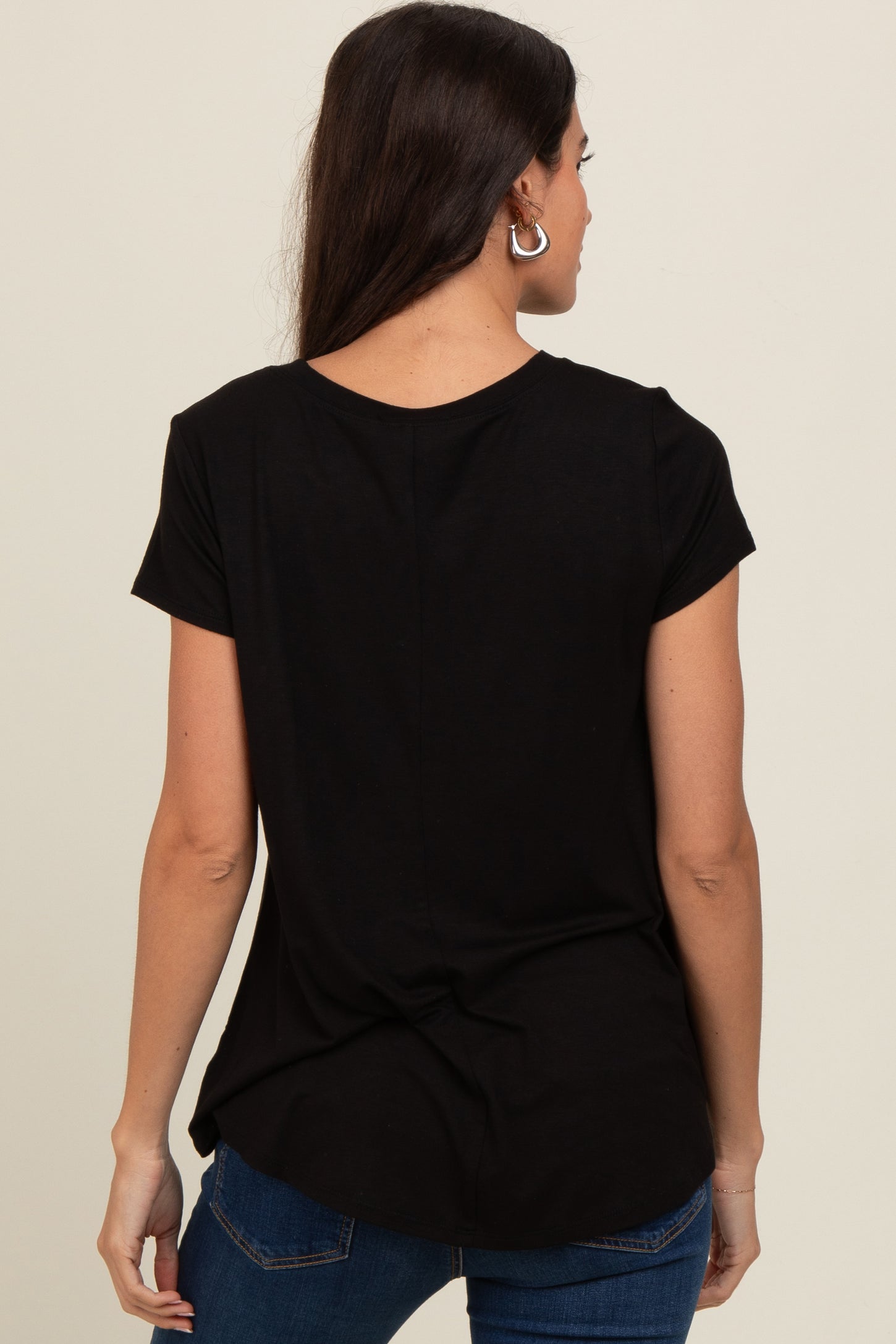 woman wearing a black short sleeve top, showing the back view with a curved hem and a relaxed fit