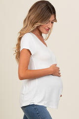 woman wearing a white short sleeve maternity top and gently holding her baby bump