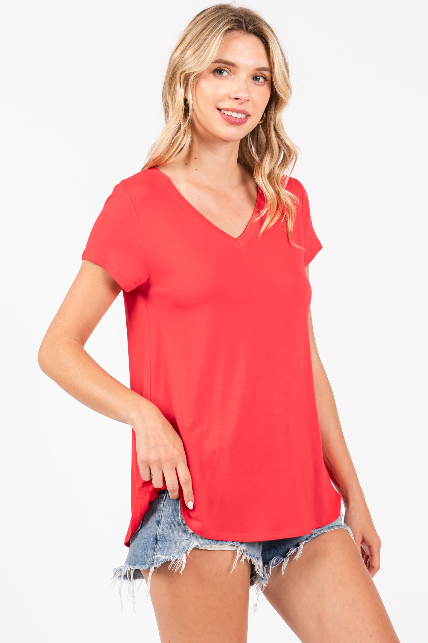 woman wearing a red v-neck short sleeve top with side slit details and denim shorts