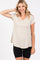 woman wearing a light beige short sleeve v-neck top with a flowy hem and black bike shorts