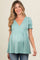 woman wearing a light teal maternity top with a v-neck and puff sleeves, showing her baby bump