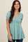 woman wearing a teal short sleeve peplum top with a v-neck and smocked sleeves