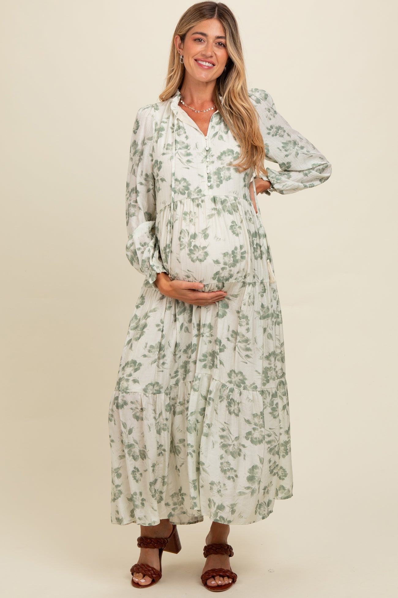 woman wearing a white floral maternity maxi dress and holding her baby bump