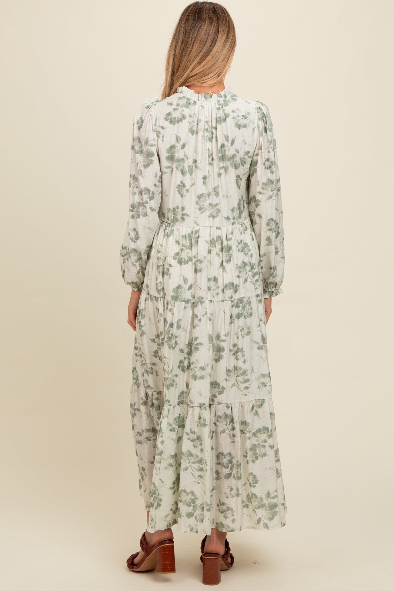 woman wearing a floral print long sleeve maternity maxi dress, showing the back view with a tiered skirt