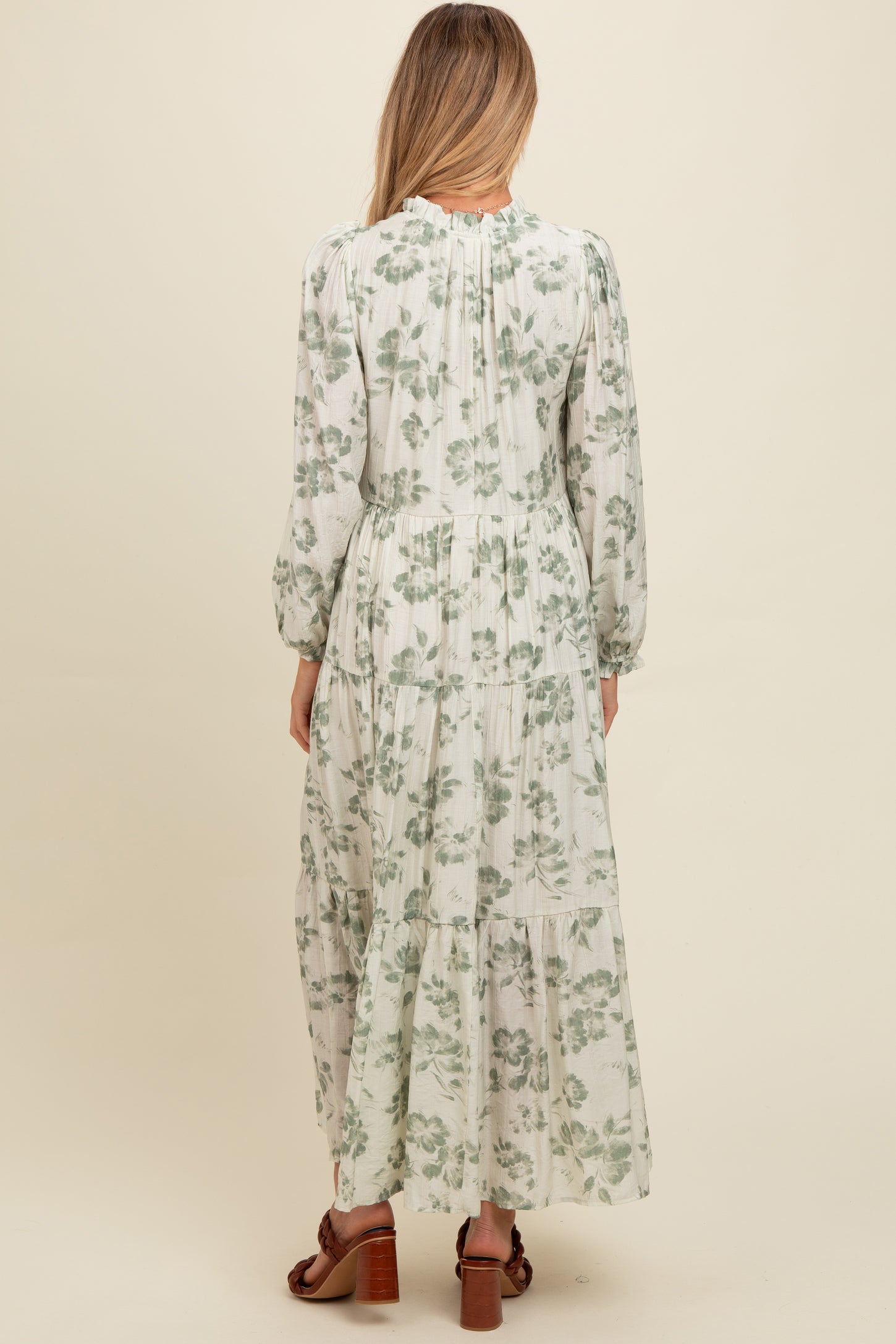 woman wearing a floral print long sleeve maternity maxi dress, showing the back view with a tiered skirt