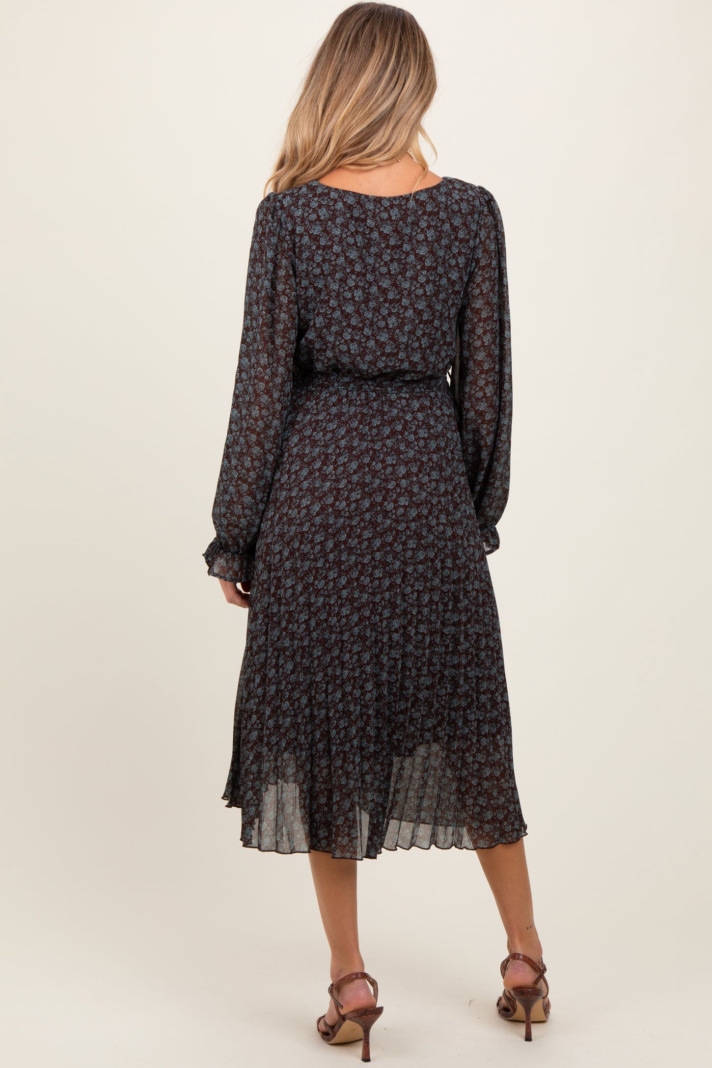 woman wearing a black floral maternity dress with long sleeves and a flowy skirt, showing her baby bump from the back