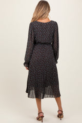 woman wearing a black floral maternity dress with long sleeves and a flowy skirt, showing her baby bump from the back