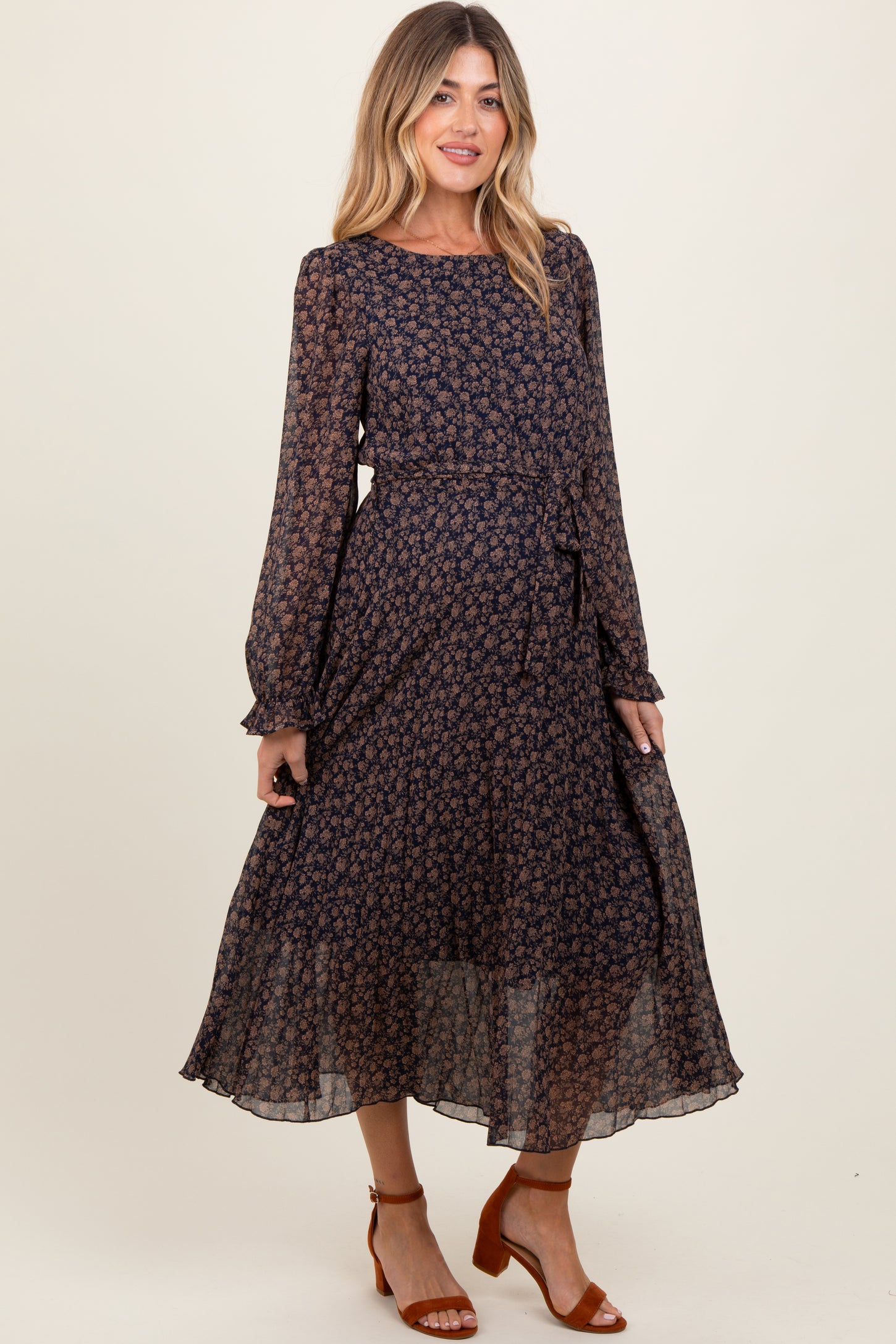woman wearing a navy blue floral maternity dress with long sleeves and a tied waist