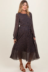 woman wearing a navy blue floral maternity dress with long sleeves and a tied waist