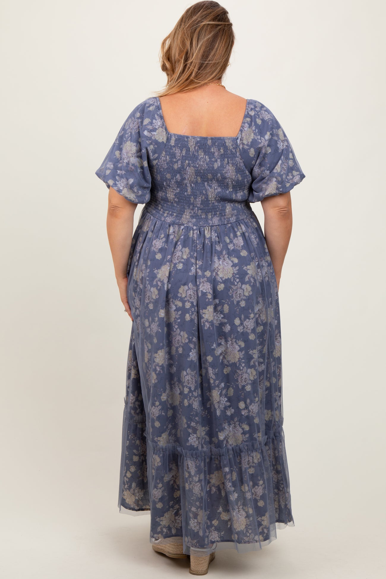plus size woman wearing a blue floral smocked back maternity maxi dress with ruffled hem