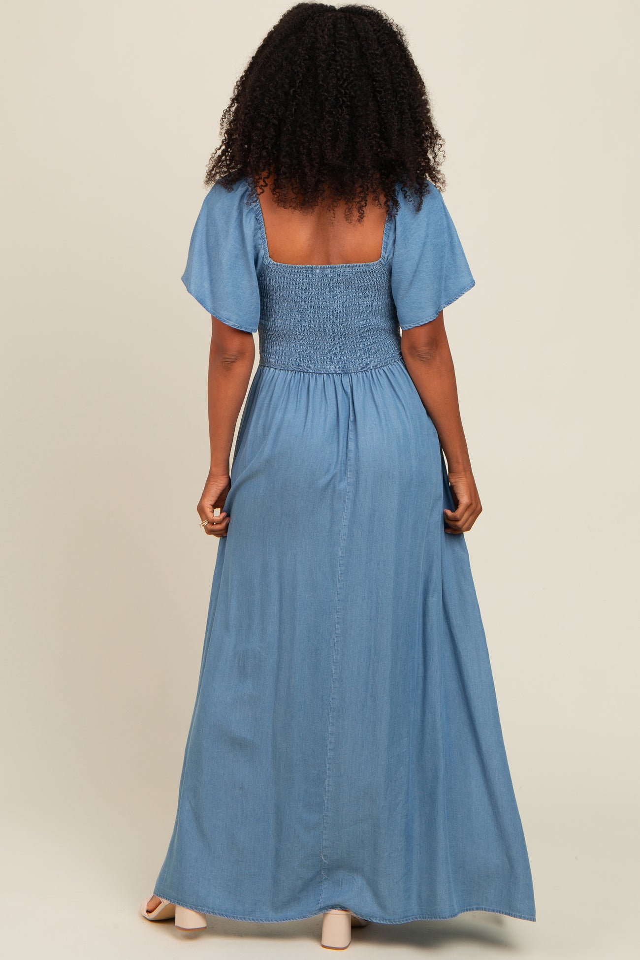 woman wearing a back view of a light blue maxi dress with smocked bodice and flutter sleeves