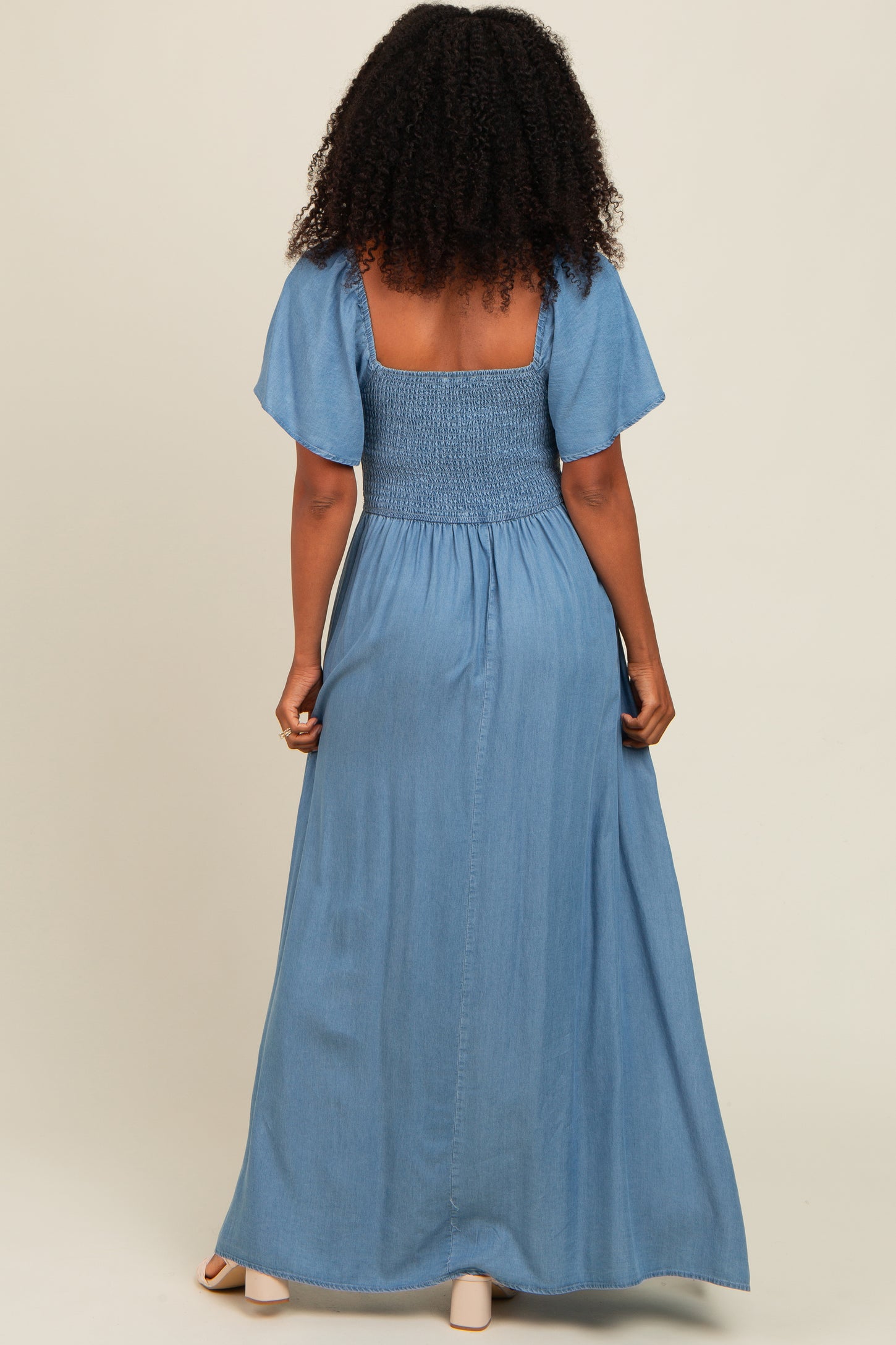 woman wearing a back view of a light blue maxi dress with smocked bodice and flutter sleeves