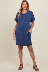 woman wearing a navy blue striped maternity dress with pockets and short sleeves, standing casually
