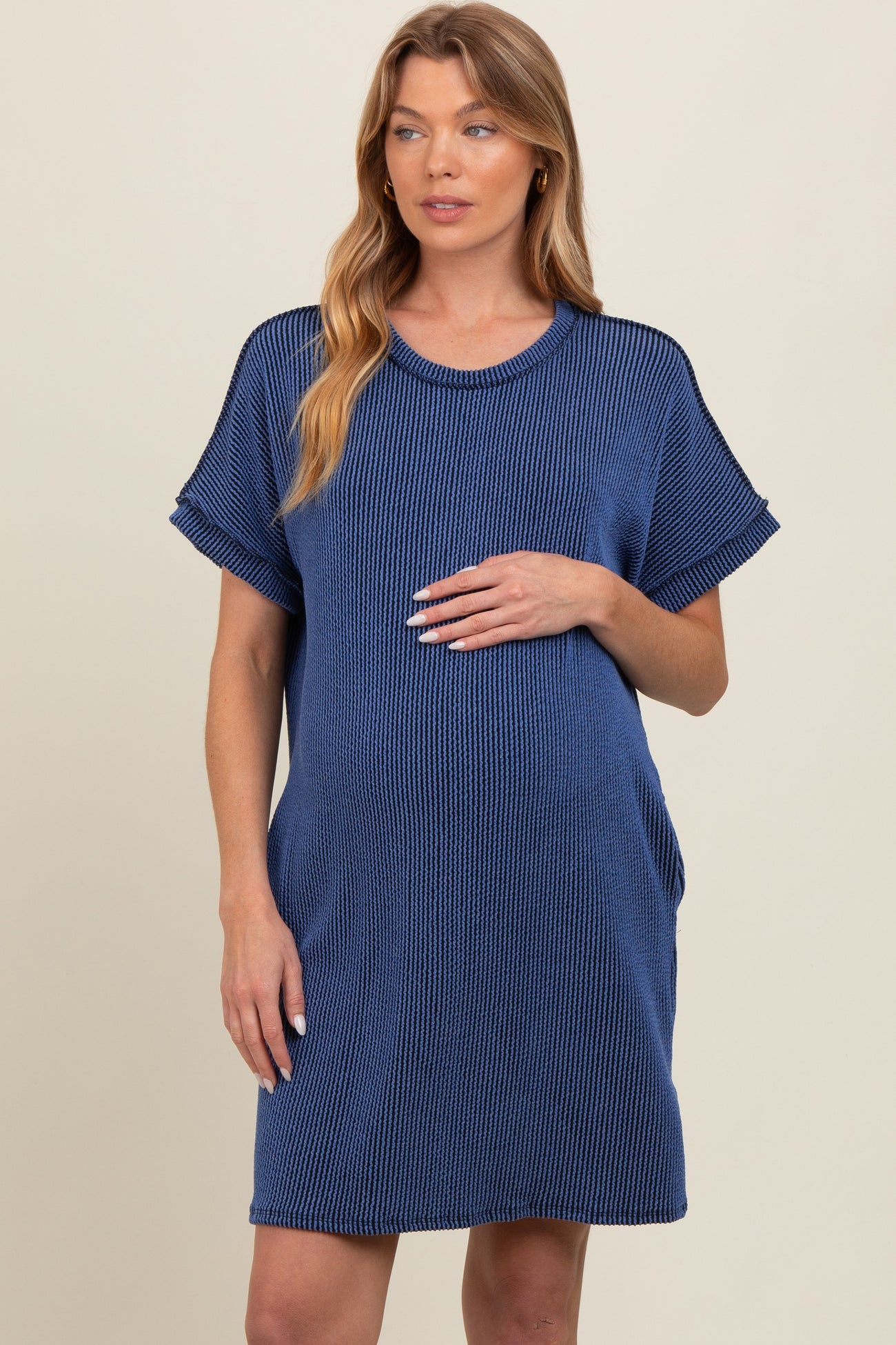 woman wearing a navy blue short sleeve maternity dress with a relaxed fit and holding her baby bump