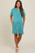 woman wearing a teal striped maternity dress with pockets and rolled sleeves, showing her baby bump
