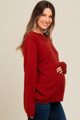 woman wearing a red maternity sweater with textured stripes and holding her baby bump