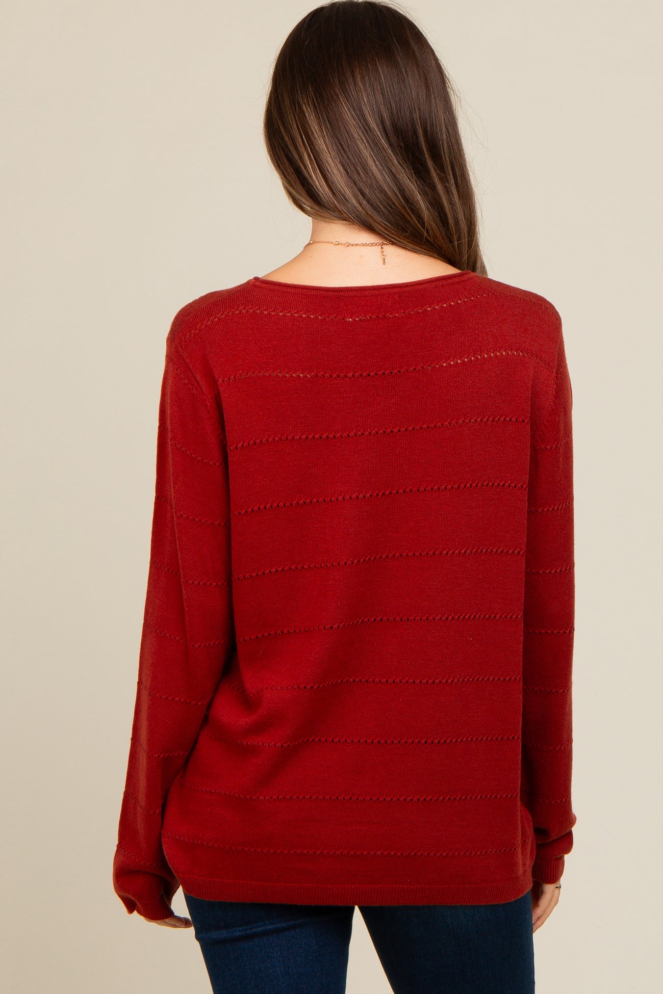 woman wearing a burgundy maternity sweater with a relaxed fit and striped detail, viewed from the back