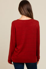 woman wearing a burgundy maternity sweater with a relaxed fit and striped detail, viewed from the back
