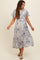 woman wearing a blue and cream floral maternity dress with short sleeves and a tie waist detail, smiling while posing