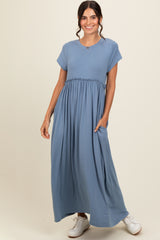 woman wearing a light blue maxi dress with short sleeves and a gathered waist, styled with white sneakers