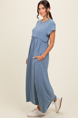 woman wearing a blue short sleeve maxi dress with an elastic waist and pockets, styled with white sneakers