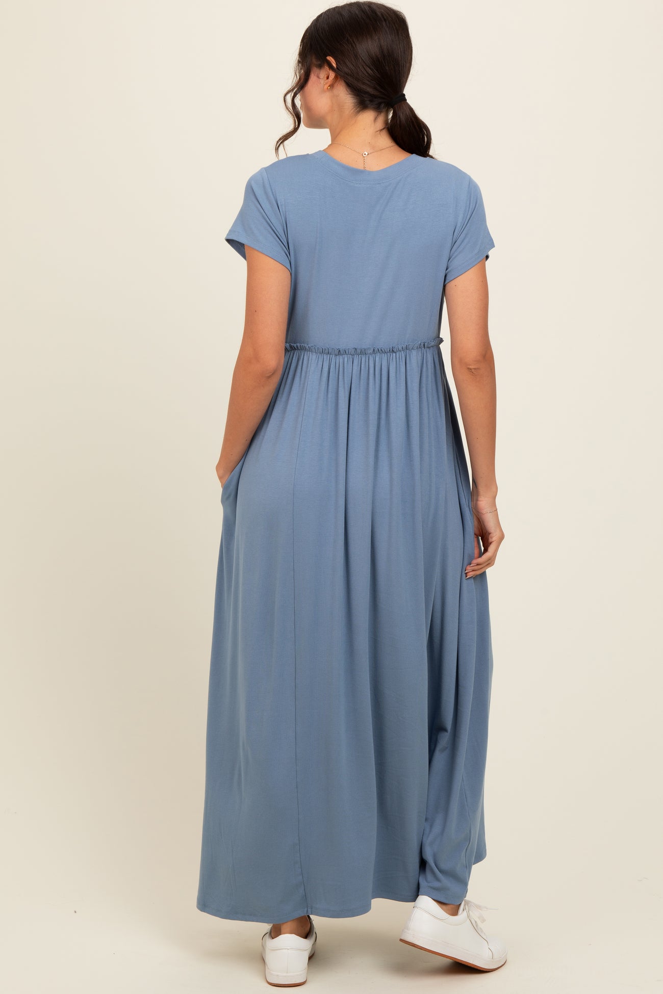 woman wearing a light blue maxi dress with short sleeves and an elastic waist, shown from the back